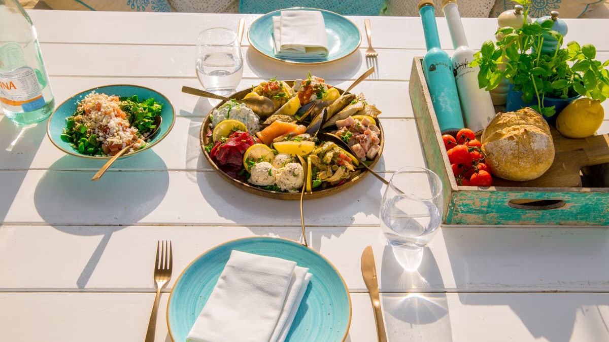 A beautifully arranged seafood platter and fresh salad on an outdoor patio table set for dining.